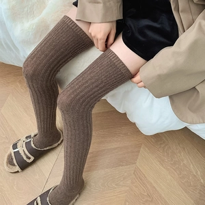 Detail of dark brown ribbed knit over-knee socks showing thick warm wool texture