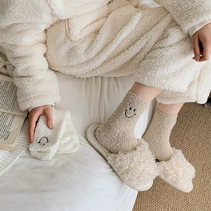 Warm coral fleece socks with smiley face embroidery and plush slippers in home setting