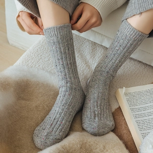 Close-up of cozy grey flecked wool socks with ribbed texture in a warm home setting