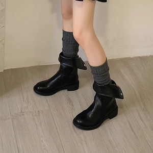 Close-up of black ankle boots with folded collar and knit wool socks for winter styling