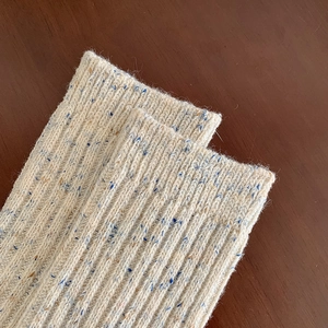 Close-up of beige wool blend rib-knit socks with blue and brown flecked texture details