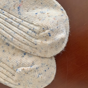 Detail of wool blend thermal socks in beige with colorful flecks and ribbed texture