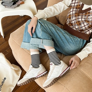 Dettaglio calzini alti a righe da donna abbinati a sneakers retrò color crema