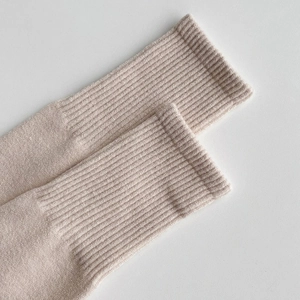 Detailed macro shot of light beige ribbed knit wool socks showing premium texture