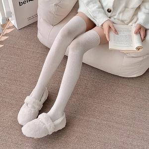 Detail view of white cable-knit over-knee socks with vertical textures for winter warmth