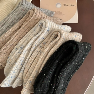 Close-up of five pairs of thick wool socks in assorted colors with knit textures