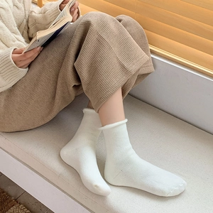 Close-up of white ribbed knit socks with cozy rolled cuffs for winter warmth
