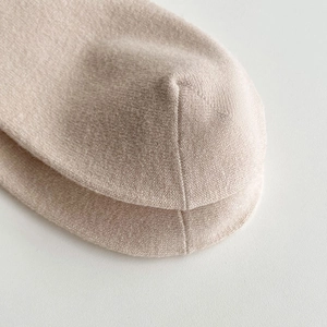 Close-up of seamless stitching and fine knit texture on beige wool over-the-knee socks