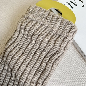 Détail macro de jambières en tricot côtelé beige avec carte de présentation jaune
