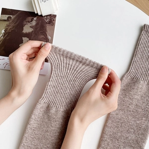 Close-up of oatmeal wool thigh-high socks showing elastic ribbed cuffs and knit texture