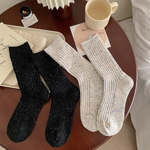 Detail of ribbed knit wool socks in black and oatmeal with colorful speckled yarn texture
