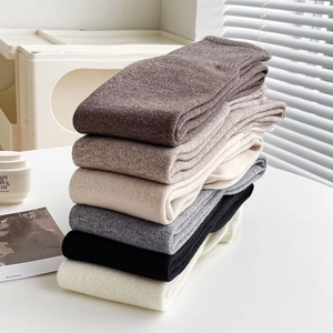 Detailed view of thick knitted over-the-knee wool socks in various warm earth tones