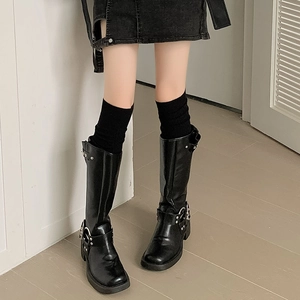 Close-up of black platform biker boots with metallic buckle straps and rivet details