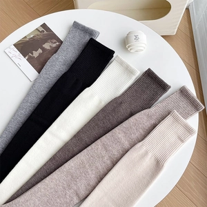 Close-up of six neutral colored wool socks featuring elastic wide ribbed cuffs on a white tray
