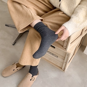 Close-up of dark grey ribbed crew socks paired with corduroy pants and suede mules