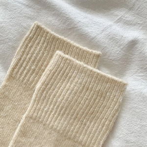 Close-up of thick beige wool knit ribbed cuffs on warm over-knee winter socks
