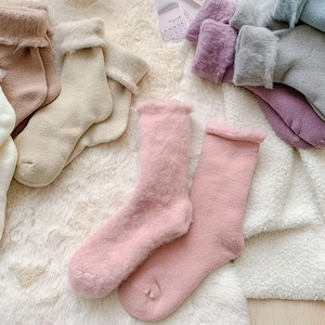 Close-up of plush thermal winter socks in pastel colors on a soft white background