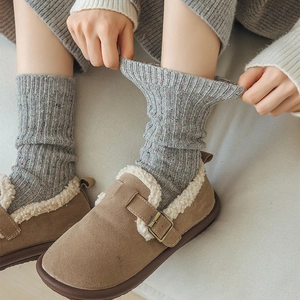 Close-up of thick gray wool socks and brown suede slippers with soft faux fur lining
