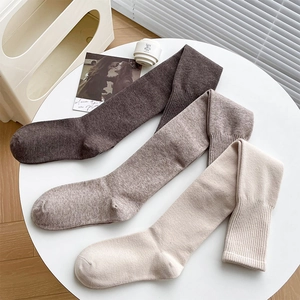Detail of wide ribbed cuffs on thick wool over-the-knee socks in brown and beige colors