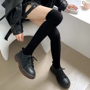 Detail of black knitted thigh-high socks with ribbed texture and platform shoes