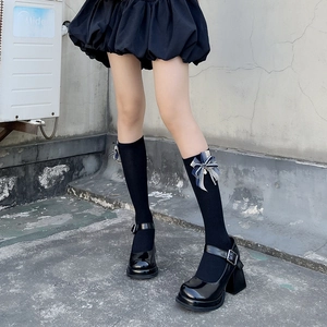 Detail of knee-high socks with blue plaid bow paired with black Mary Jane shoes