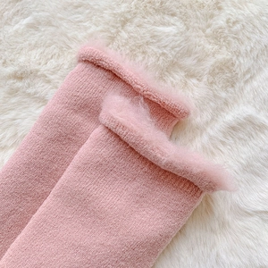 Close-up of pink knit winter socks featuring soft faux fur trim and warm fuzzy texture