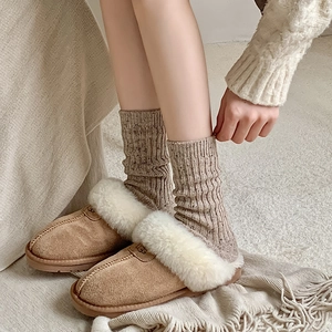 Close-up of cozy brown suede slippers with white faux fur lining and knit wool socks