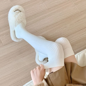 Detail of white thigh high knit socks with vertical ribbed texture for warm home comfort