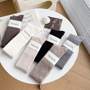 Folded thick wool over-the-knee socks in six neutral colors with branded paper wraps