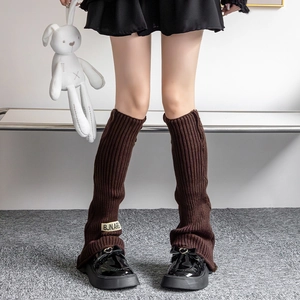 Detailed knit texture of dark brown leg warmers with a white fabric brand label