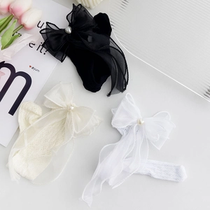Detailed view of lace bow knee socks in black, cream and white with pearl accents
