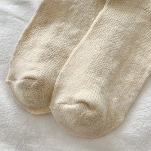 Close-up of oatmeal knitted over-knee socks showing soft wool texture and toe stitching