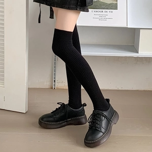 Detail of black ribbed knit over-the-knee socks paired with platform lace-up shoes