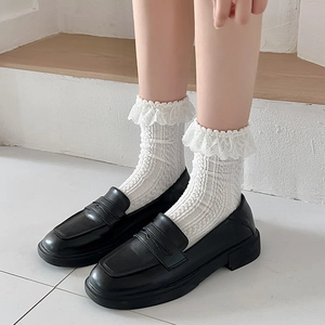Detail of Lolita style white lace socks with cable knit texture and black loafers