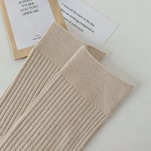 Detail of oatmeal ribbed knit over-knee socks featuring soft texture and elastic cuff