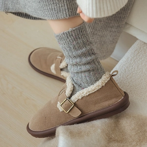 Detail of warm brown suede mule with white faux fur lining and metal buckle accent