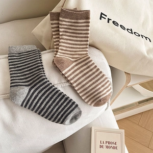 Dettaglio di calze a righe in cotone con trama a maglia nei colori grigio e marrone