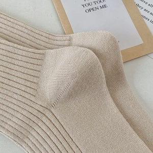 Close-up of oatmeal beige knit over-knee socks featuring vertical ribbed texture details