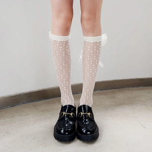 Detail view of white lace hollow mesh knee high socks with silk ribbon bow accents
