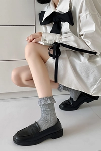 Detailed view of grey knit Lolita socks with lace trim paired with black loafers