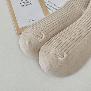 Close-up of thick beige ribbed knit over-knee socks with soft elastic texture detail