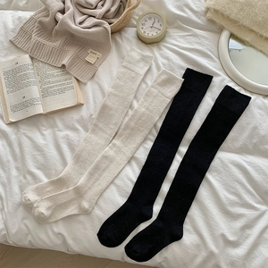 Detail of thick over-the-knee socks in black and off-white with ribbed anti-slip cuffs