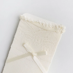 Detail von weißen hohlen Spitzensocken mit floralem Netzmuster und Satin-Schleifendekor