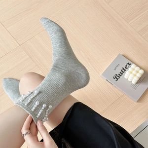 Détail de chaussettes grises côtelées ornées de perles blanches élégantes et douces