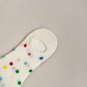 Detailed mesh view of white low-cut socks with colorful polka dots and non-slip heel grip