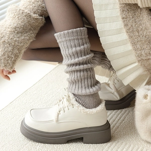 Détail de chaussettes plissées en tricot portées avec des mocassins fourrés beiges