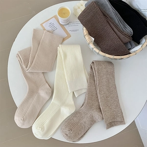 Close-up of thick ribbed knit over-the-knee socks in a variety of neutral autumn colors