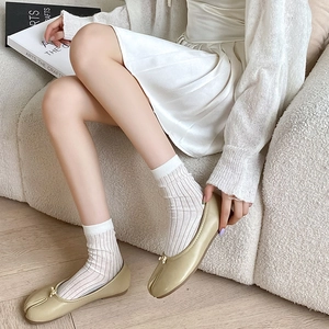 Dettaglio di ballerine Tabi verde chiaro con fiocco e calze bianche a coste in casa