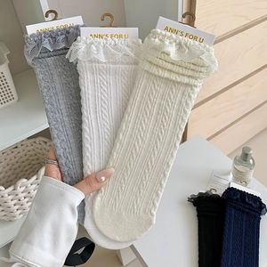 Close-up of cable knit texture and delicate lace trim on Lolita style cotton socks