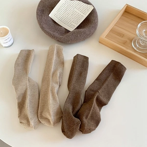 Detailed view of four pairs of ribbed knit crew socks in earth tones with stylish props
